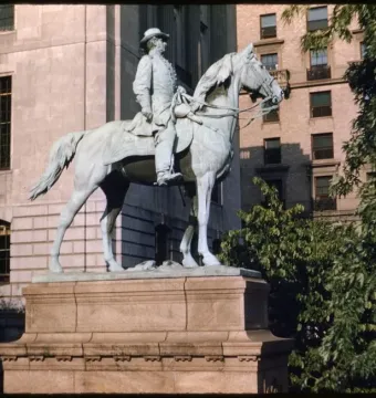 Joseph Hooker statue depicting a bronze equestrian figure on a multi-tiered stone pedestal, surrounded by trees and city buildings.
