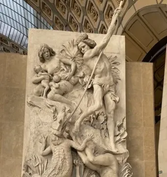 The Nubians relief showing a figure raising a spear over a large reptile while another lies fallen below, with a seated figure holding two infants in the background.