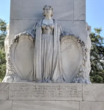 A classical female figure on the Alamo Cenotaph holds shields above inscribed panels.