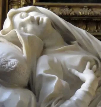 Detail of Ecstasy of Blessed Ludovica Albertoni, showing the marble figure reclined with eyes closed and a hand resting on the chest.