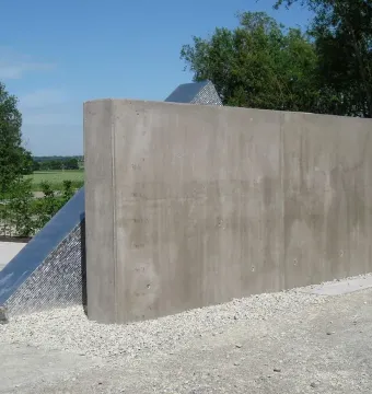 Hailfingen-Tailfingen Memorial with a tall concrete wall and angular metal structure beside it.