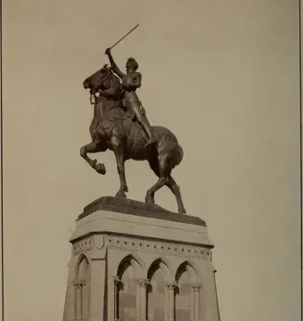 Joan of Arc equestrian statue with an armored figure raising a sword on a rearing horse atop a tiered stone pedestal.