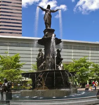Tyler Davidson Fountain with a robed figure and smaller bronze figures in a city plaza
