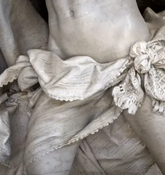 Close-up of the Angelo Nocchiero sculpture showing marble drapery tied at the waist over the figure\'s midsection.
