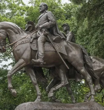 Robert E. Lee equestrian statue with a bearded rider on horseback, raising his hat, and a second mounted figure behind him.