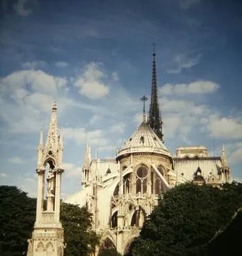 Fontaine de la Vierge monument in front of Notre-Dame Cathedral with flying buttresses and spire in the background.