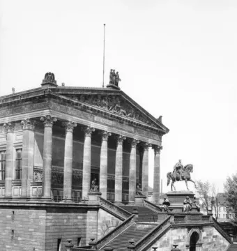 Frederick William IV equestrian statue on a tall stone pedestal with allegorical figures, set before a classical building and staircase.