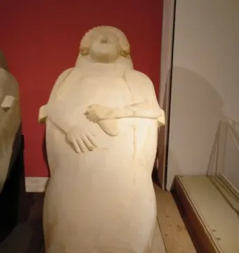 Lady of Cádiz stone sculpture of a woman with curly hair and hands resting over her midsection.