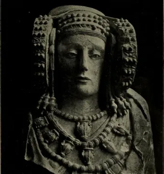 Stone bust of the Lady of Elche with an ornate headdress and layered necklaces.