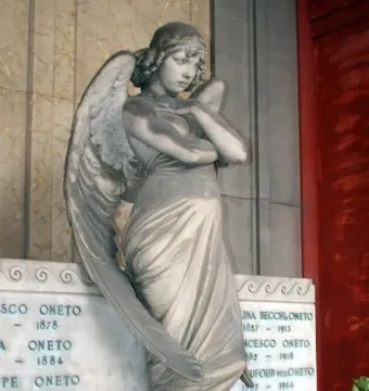 Monteverde Angel marble sculpture of a winged angel with folded arms and bowed head beside inscribed grave panels.