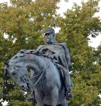 Monument to General Martínez-Campos, a weathered bronze equestrian statue against leafy trees.