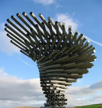 The Singing Ringing Tree sculpture made of grey metal pipes against a blue sky.