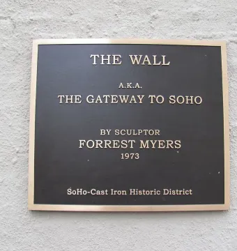 A dark metallic plaque for The Wall mounted on a light textured wall.