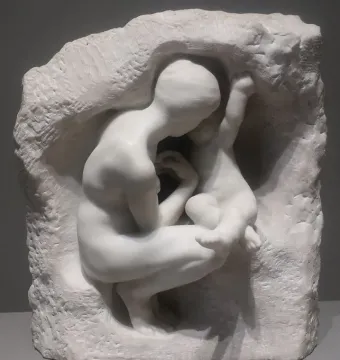 Young Mother in the Grotto, a white marble sculpture of a crouching mother embracing a child within a rough grotto-like form.