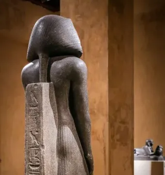 Back view of the Amenemhat III statue showing a striped nemes headdress and a hieroglyph-inscribed back pillar.