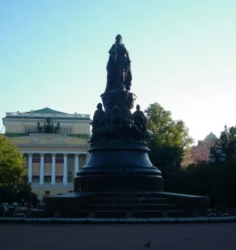 Catherine II Monument rising above a paved square under a clear blue sky, with a central figure and smaller seated figures on the pedestal.