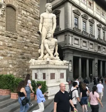 Hercules and Cacus sculpture on an ornate pedestal in Piazza della Signoria, showing two muscular figures in white marble.