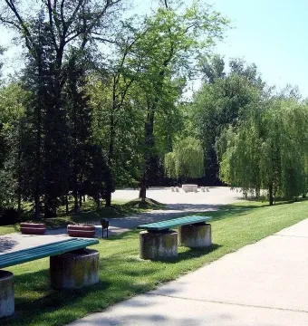 Table of Silence surrounded by hourglass-shaped chairs in a park setting.