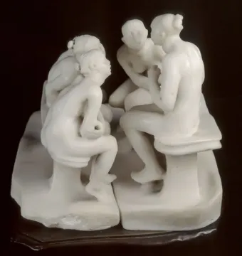 The Confidence marble sculpture showing four seated women in two facing pairs against a dark background.