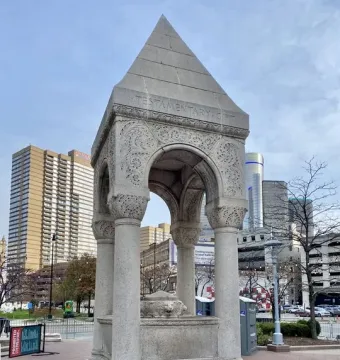 Bagley Memorial Fountain with a pyramidal roof, carved arches, and a lion-head relief in Detroit\'s Cadillac Square.