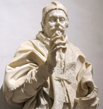 White marble bust of Pope Clement X with a cap, mustache, and small beard, wearing elaborate clerical vestments and holding beads near his mouth.