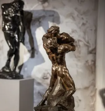 Je suis belle bronze sculpture showing two intertwined muscular figures on a rough base.