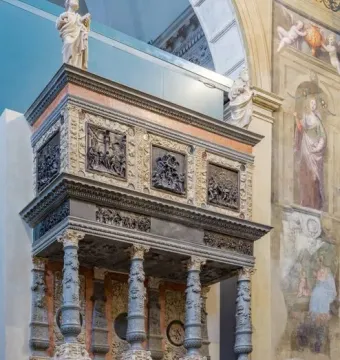 Martinengo Mausoleum with carved grey columns, a relief frieze, and small statues at the top inside a painted interior wall.