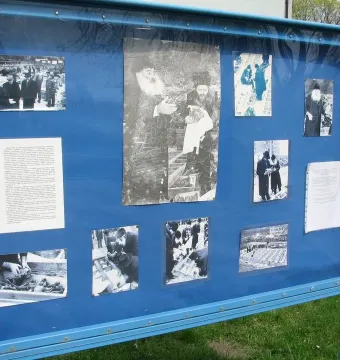 Blue display board for the Monument of Common Martyrdom, covered with historical photographs and text documents.