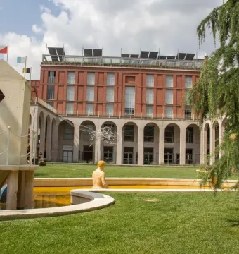 The Mystery Baths fountain with a golden bather statue beside a small angular tower-like structure in a park.