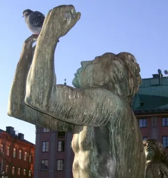 Close-up of the Orpheus Fountain bronze statue with a pigeon perched on its raised hand.
