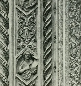 Close-up of the Porta della Mandorla showing twisted columns and carved relief panels with putti, an angel holding a scroll, and foliate ornament.