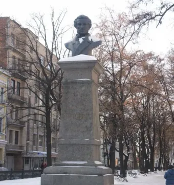 Bust of Pushkin on a tall stone pedestal in a snowy outdoor setting.