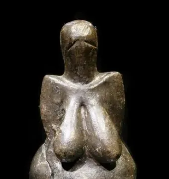Venus of Dolní Věstonice figurine with pronounced breasts and belly, shown with visible cracks and no facial features.