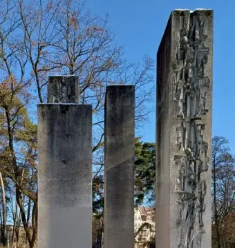 Julius Fučík Memorial with three tall stone steles in a snowy park, one carved with relief figures and abstract shapes.