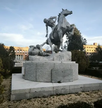 The Torch Bearers sculpture shows a rearing horse and two figures on a circular pedestal in a landscaped outdoor setting.