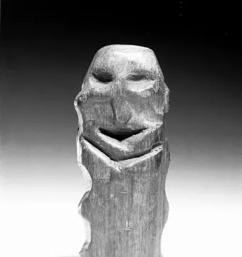 Mannetje van Willemstad wooden carving with carved facial features against a dark background.