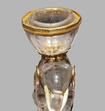 Rock crystal elephant with gold-colored tusks, ears, and feet carrying a faceted salt vessel.