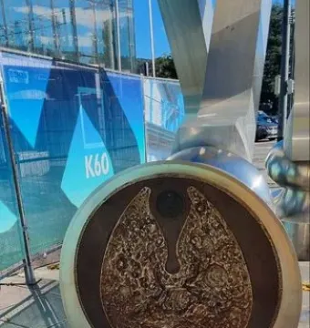 Close-up of the S-Printing Horse base with a textured bronze-colored circular metal plate and an embedded light on the paved ground.