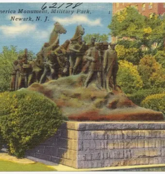 Wars of America monument showing multiple figures and mounted riders atop a stone base in a landscaped park setting.