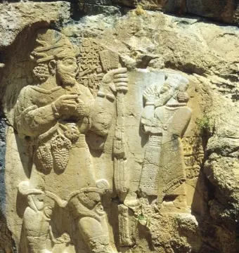 Ivriz relief showing two carved figures, one holding a staff and grapes.