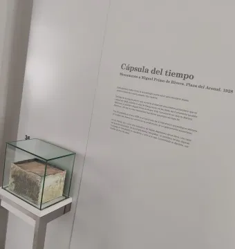 A glass display case showing an aged box, with a Spanish information panel about the Monument to Primo de Rivera time capsule beside it.