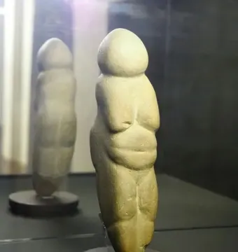 Venus of Chiozza figurine displayed on a dark circular base inside a case.