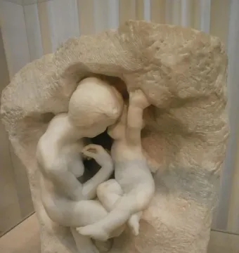 Young Mother in the Grotto, a white marble sculpture of a woman and child nestled inside a rough cave-like form.