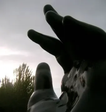 Fernando Botero\'s Hand sculpture silhouetted against a bright overcast sky.