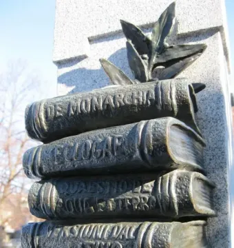 Book-shaped reliefs on La mort de Dante, including embossed titles and sculpted leaves above a granite surface.