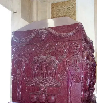 Sarcophagus of Constantina with carved grape-harvesting figures and vines on a red porphyry surface.