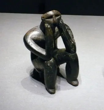 The Thinker of Cernavodă figurine seated with its head resting on its hands.