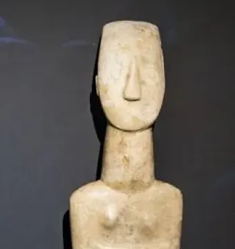 Cycladic marble female figurine with folded arms and a long neck.