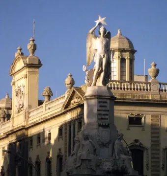 Genio Catalán Fountain with a winged male figure holding a star atop its pedestal and seated figures around the base