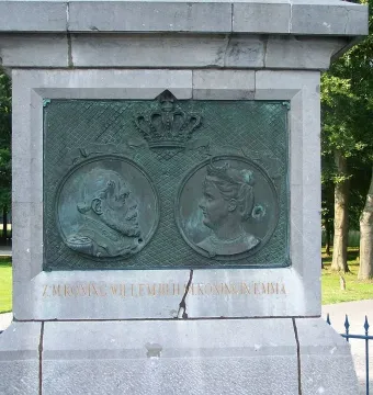 The Needle monument plaque with profile busts of King Willem III and Queen Emma beneath a crown.